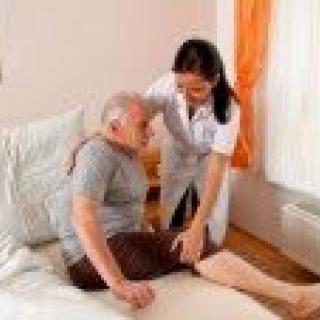A nurse assists an elderly man in getting out of bed.