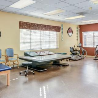 A well-equipped rehabilitation therapy room with exercise equipment and seating areas.