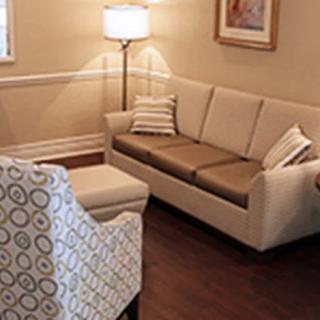 A cozy living room featuring a beige sofa, patterned armchair, and warm lighting.