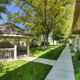 A peaceful residential area with a gazebo and a tree-lined sidewalk on a sunny day.