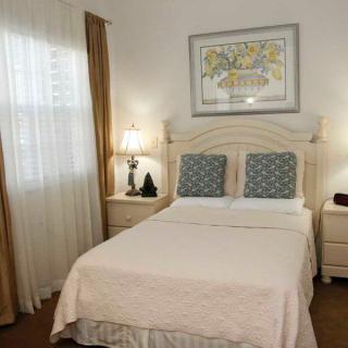 Cozy bedroom with a neatly made bed, bedside lamps, and framed artwork.