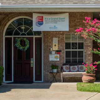 A quaint building entrance with a welcoming bench and vibrant flowers.