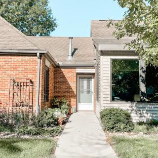 A suburban brick house with a landscaped front yard and a pathway leading to the entrance.
