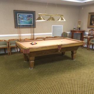A well-furnished game room featuring a pool table surrounded by chairs and decorated with wall artwork.