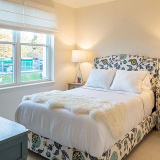 A cozy bedroom with a floral-patterned bed and a soft ambient glow from the lamp.