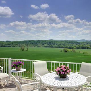 A serene patio overlooking a vast green countryside landscape under a clear blue sky.