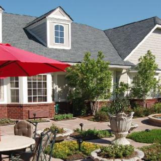 A charming house with a well-maintained garden and patio area, featuring outdoor seating under a red umbrella.