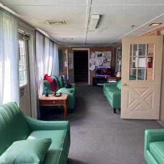 A cozy lobby area with green couches and natural light streaming through curtained windows.