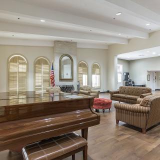 A spacious and elegantly furnished lounge with a grand piano, comfortable seating, and large windows.