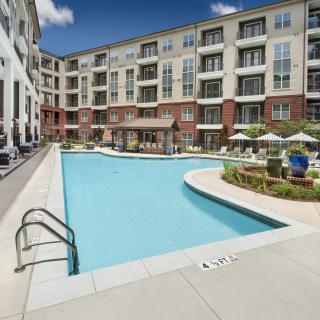 A modern apartment complex with an outdoor swimming pool and patio area.