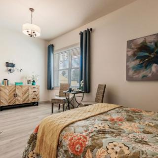 A cozy bedroom interior with floral bedding, modern furniture, and elegant decor.
