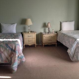 A cozy bedroom featuring two neatly made single beds with nightstands and lamps.
