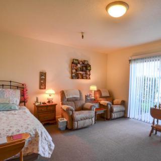 A cozy bedroom interior featuring a bed, comfortable chairs, and warm lighting.