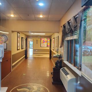 A view of a well-lit hallway adorned with artwork and featuring large windows.