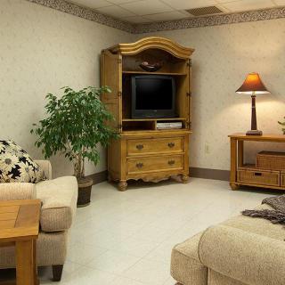 A cozy living room with a television on a wooden cabinet, surrounded by sofas and a lamp.