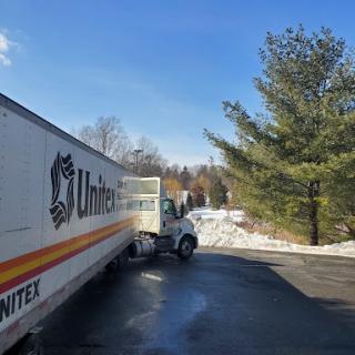 A moving truck parked on a snowy road under a clear blue sky.