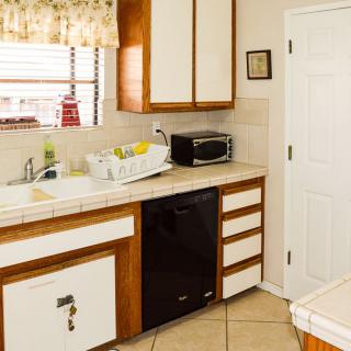 A cozy kitchen interior featuring a sink, microwave, dish rack, and wooden cabinets.