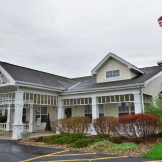 A suburban residential building with a well-maintained garden and driveway under an overcast sky.
