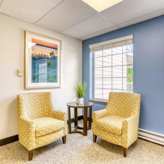 A cozy seating area with two patterned chairs, a small table, and a window providing natural light.