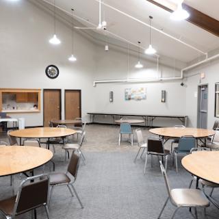 A spacious community room featuring circular tables and chairs, perfect for gatherings and events.