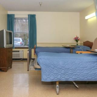 A hospital room with two beds and a TV.
