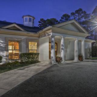 A beautifully lit house exterior with classic columns and a porch at night.