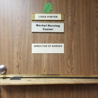 An office door with nameplates indicating the director of nursing at a nursing center.