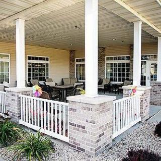 A cozy outdoor patio area with white railings and brick pillars.