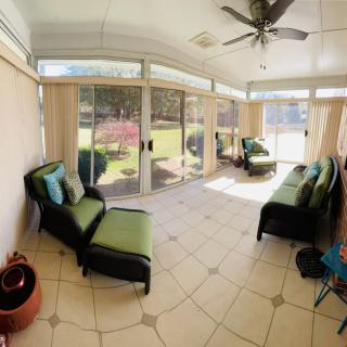 A bright sunroom with comfortable seating and large glass doors offering an outdoor view.