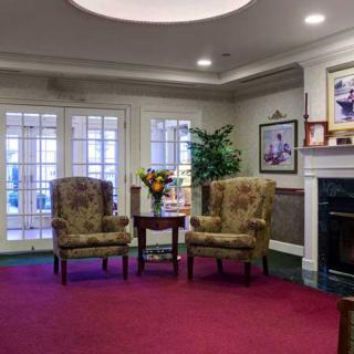 A cozy living room with armchairs, a fireplace, and traditional decor.