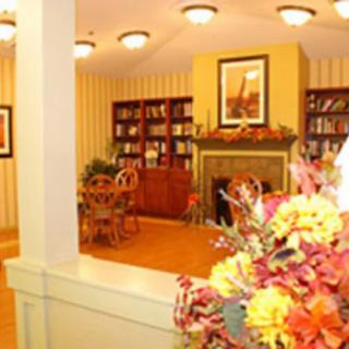 A cozy library interior featuring bookshelves, a fireplace, and floral decorations.