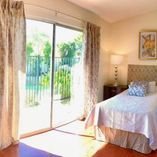 A bright and airy bedroom with a bed, lamp, and large sliding glass doors leading to a garden.