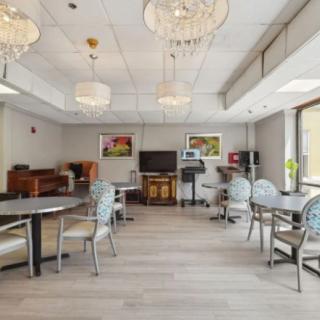 A modern dining room with chandeliers, tables, and chairs on a wooden floor.