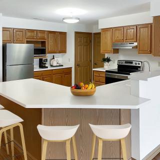 A modern kitchen with wooden cabinets, a large countertop, and bar stools.