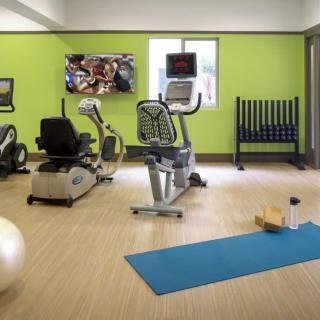 A well-equipped gym room featuring exercise machines and a yoga area.