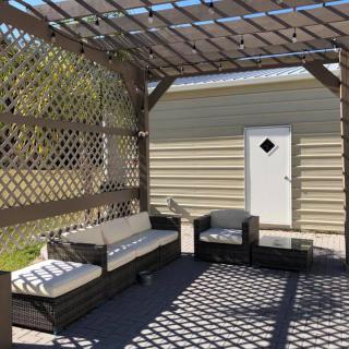 A cozy outdoor seating area under a pergola with lattice walls and stylish furniture.