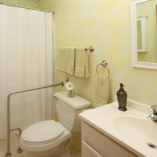 A clean and simple bathroom with a toilet, sink, mirror, and shower.