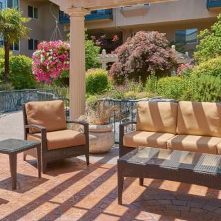 A cozy outdoor patio with garden seating and scenic landscaping on a sunny day.