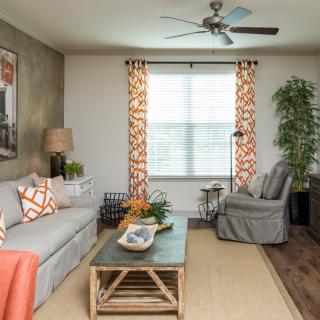 A cozy living room with a sofa, armchair, and coffee table, featuring stylish curtains and a decorative plant.