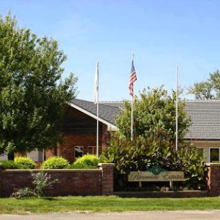 A welcoming community center with well-maintained landscaping and flags waving under a clear blue sky.