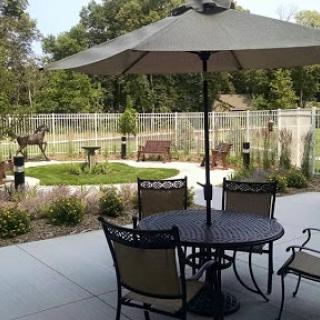 A serene outdoor patio area featuring a table with chairs under an umbrella, overlooking a garden.