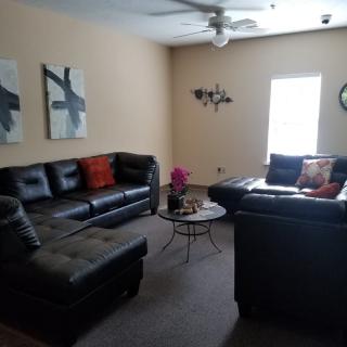 A cozy living room with dark leather sofas, abstract artwork, and a central coffee table.
