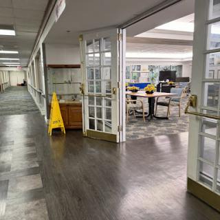 A view of an office corridor leading to a workspace with a cleaning sign.