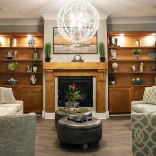 A modern living room featuring a central fireplace, elegant shelving, and comfortable seating with a statement chandelier.