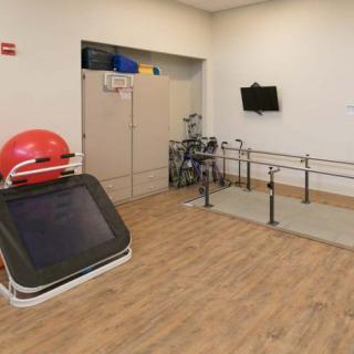 A rehabilitation room equipped with parallel bars and exercise equipment.