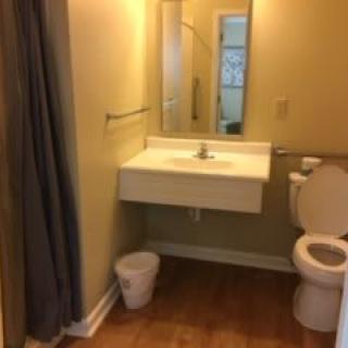 A small bathroom featuring a sink, toilet, and shower area.