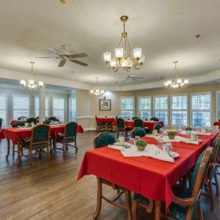 A spacious dining room with red tablecloths and elegant chandeliers.