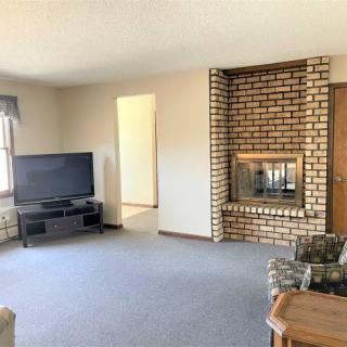 A cozy living room featuring a brick fireplace and a television.