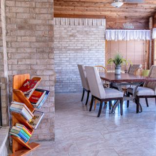 A cozy dining area featuring a wooden table and elegant chairs, complemented by a stylish bookshelf filled with books.