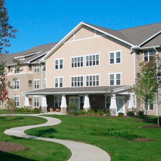 A modern residential apartment building with a well-maintained lawn and a winding pathway.